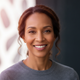 A happy, confident woman in her 40s smiles directly at the camera, conveying satisfaction and trust.